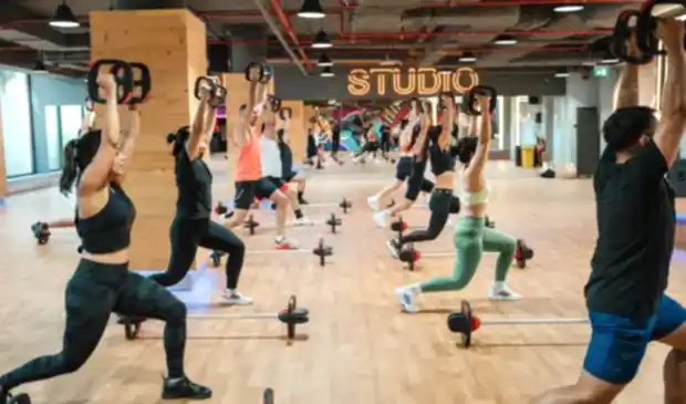 Group of people doing Les Mills BODYPUMP class at GymNation Dubai, using barbells and SMARTBAR equipment